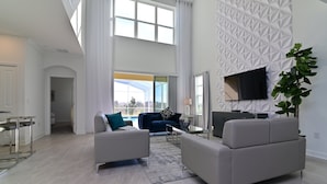 En rummelig stue med højt til loftet, stort vindue og moderne vægdesign.