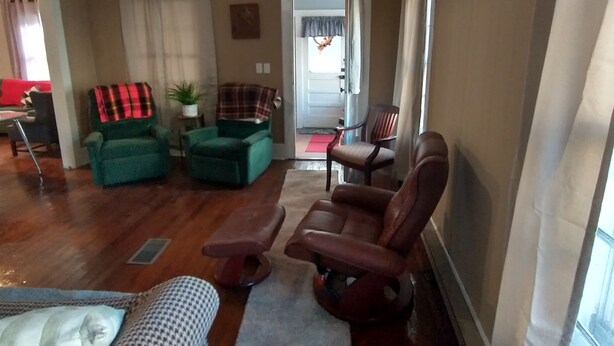 A living room with a ceiling fan, a green armchair, a brown armchair, a patterned ottoman, and a blue rug. - DUPLEX....and yes you get the whole house!!! (Northfork)