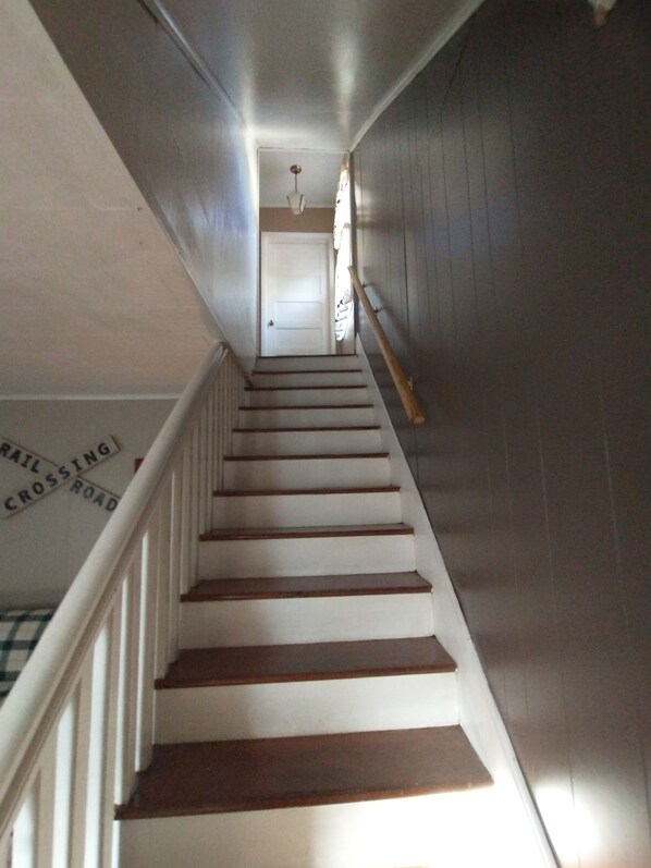 A staircase with wooden steps and white railings, leading to a door at the top.