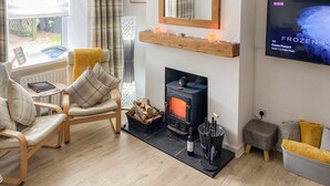 Una sala de estar acogedora con chimenea, televisor montado en la pared y un espacio de estar cómodo.