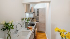 Eine moderne Küche mit Spüle, Herd und Kühlschrank. Auf der Arbeitsplatte stehen Blumen und ein Strauß gelber Blumen.