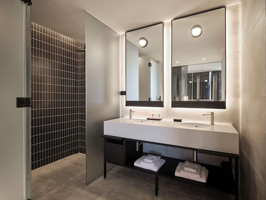 Een moderne badkamer met een grote spiegel, twee wasbakken en een handdoekrek.