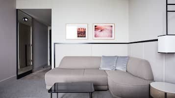 Et moderne hotelværelse med en grå sofa, et lille bord og to billeder i rammer på væggen.