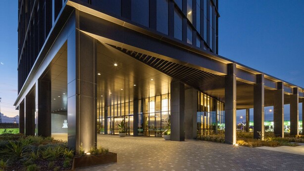 A modern building with a covered entrance, large windows, and a well-lit lobby area. - Hyatt Place Melbourne, Caribbean Park (Scoresby)