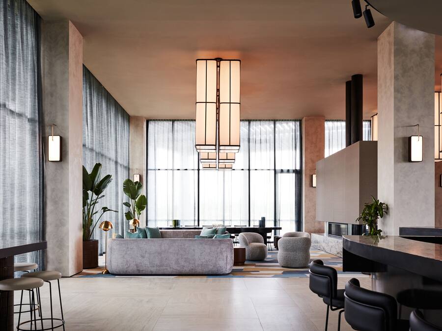 A modern hotel lobby with a large seating area, a bar, and large windows.