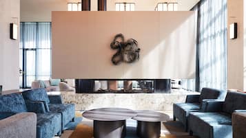 Una sala de estar moderna con sofás azules, una chimenea y un elemento decorativo en la pared.