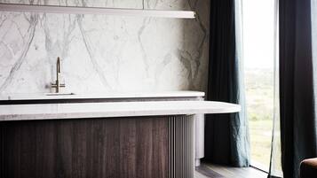 Un baño moderno con pared de mármol, tocador de madera y ventana con cortinas.