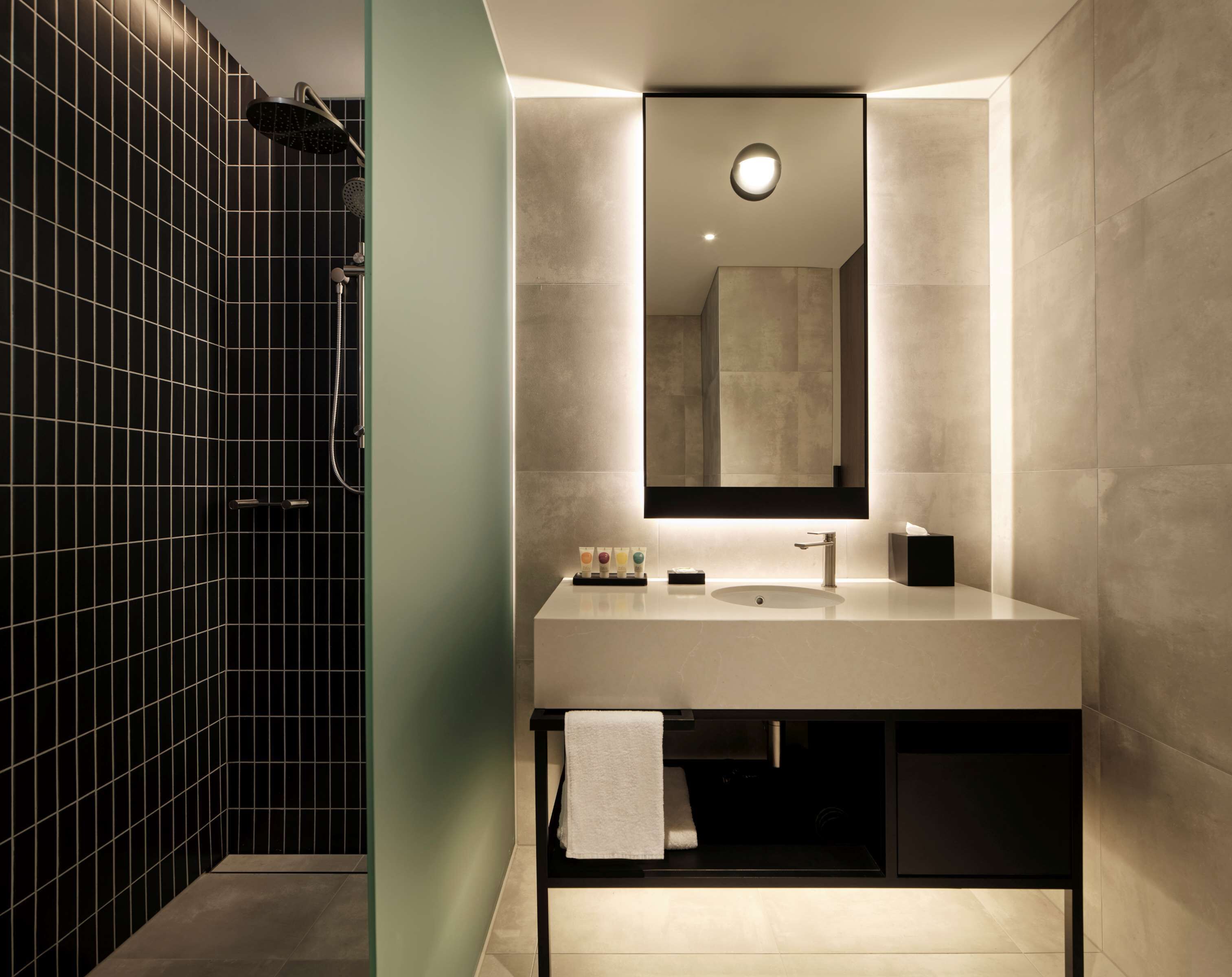 A modern bathroom with a large mirror, a sink, and a shower.
