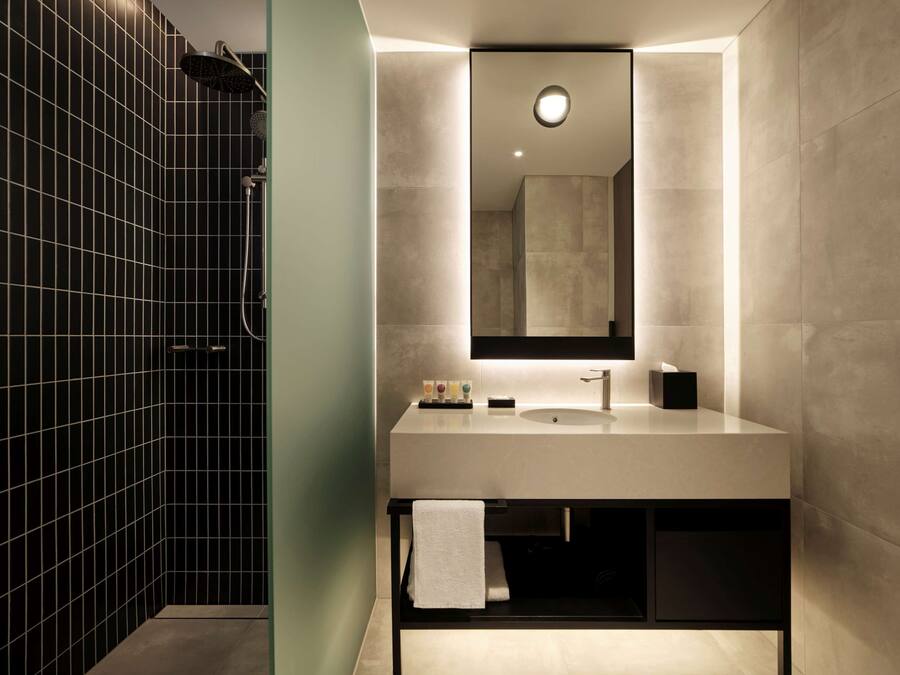 A modern bathroom with a large mirror, a sink, and a shower.