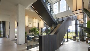 A spacious lobby with a central staircase, large windows, and modern lighting fixtures. - Hyatt Place Melbourne, Caribbean Park (Scoresby)