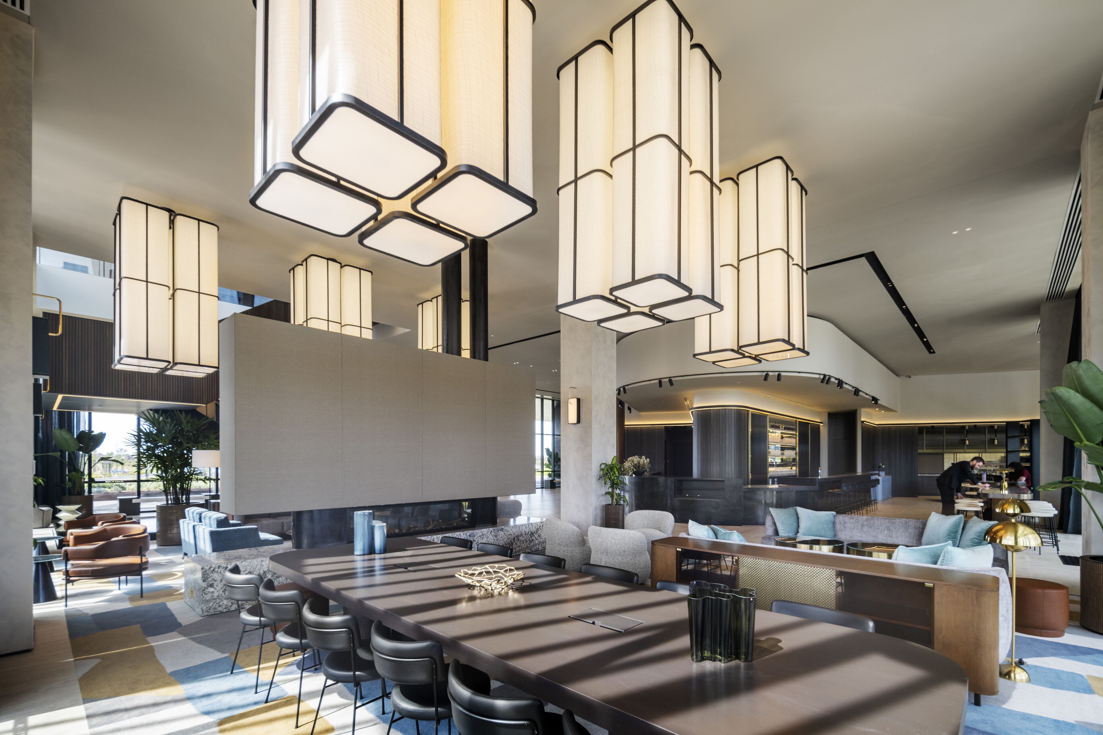Eine geräumige, moderne Hotelhalle mit einer großen Sitzecke, einer Bar und einer Küche im Hintergrund.