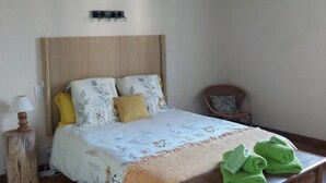 A bedroom with a bed, bedside table, lamp, and a wooden bench with towels. - O Nature, cherish my wishes before they run away (Francescas)