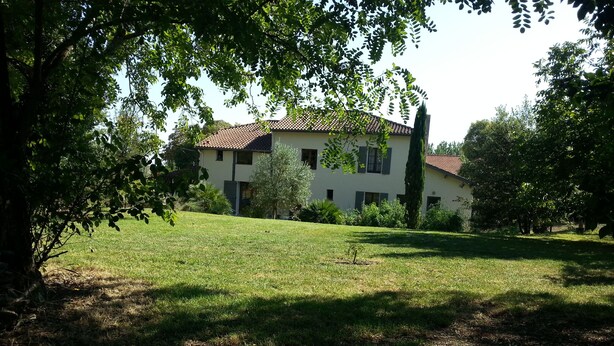 A two-story building with a tiled roof, surrounded by a grassy lawn and trees. - O Nature, cherish my wishes before they run away (Francescas)