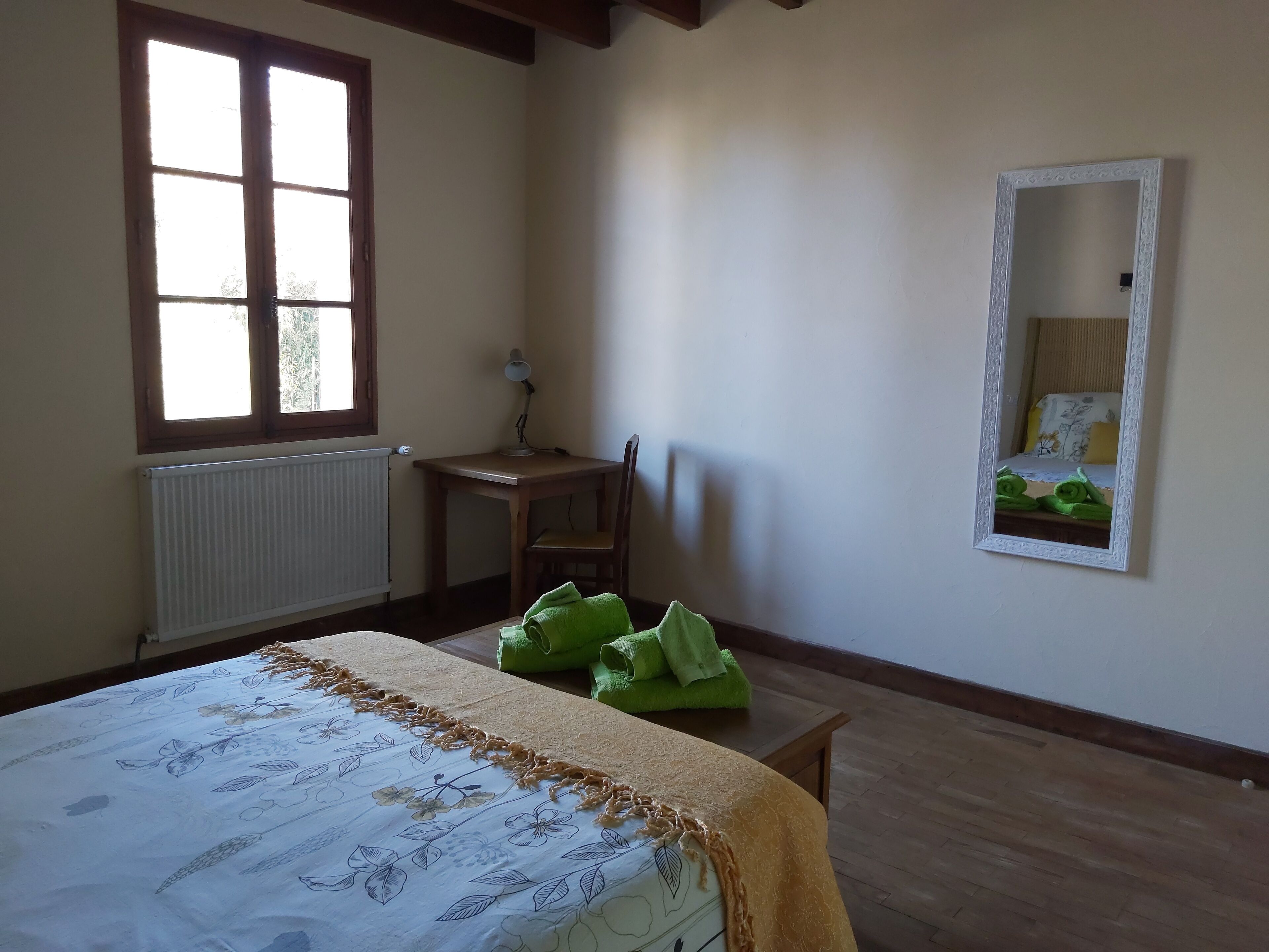 Een slaapkamer met een bed, een bureau, een stoel, een radiator en een raam.