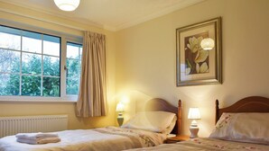 A hotel room with two beds, a window with curtains, a radiator, and a framed picture on the wall. - Ideally positioned in a peaceful location enjoying extensive fell views. (Keswick)