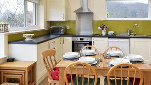 A modern kitchen with a dining area, featuring a stove, oven, and microwave. - Ideally positioned in a peaceful location enjoying extensive fell views. (Keswick)