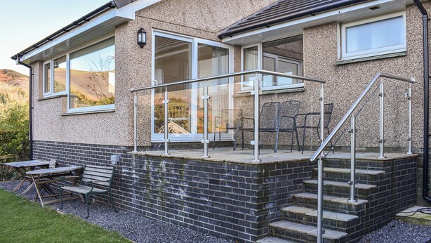 A two-story house with a stone facade, large windows, and a balcony with metal railings. - Ideally positioned in a peaceful location enjoying extensive fell views. (Keswick)
