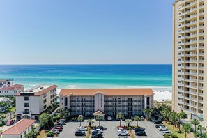 A hotel with a central building, parking lot, and a beach view. - Windancer 201. Gulf Front, Free Beach Service, Pool, Grill, Beautiful Views! (Miramar Beach)
