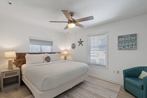 A bedroom with a bed, two bedside tables, a ceiling fan, and a blue armchair. - Windancer 201. Gulf Front, Free Beach Service, Pool, Grill, Beautiful Views! (Miramar Beach)