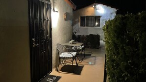 A patio with a table and chairs, a black gate, and a doormat with "hello" written on it. - Villa E - a cozy studio in the heart ♥️ of downtown Palm Springs! (Palm Springs)