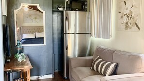 A cozy living area with a sofa, a coffee table, a TV, and a refrigerator. - Villa E - a cozy studio in the heart ♥️ of downtown Palm Springs! (Palm Springs)