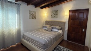 A bedroom with a bed, a ceiling fan, a wooden door, and two wall-mounted lights. - Villa E - a cozy studio in the heart ♥️ of downtown Palm Springs! (Palm Springs)