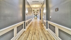 A hallway with a wooden floor, grey walls, and white trim. There are wall sconces and a chandelier. - Labor Day Is Available Breathe Taking North Beach Resort Ocean Front Condo (North Myrtle Beach)