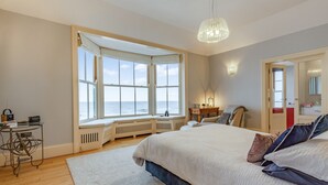 A bedroom with a large window, a bed, a desk, and a chair. - 2 bedroom accommodation in Cromer (Cromer)