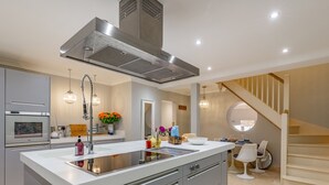 A modern kitchen with a large island, stainless steel appliances, and a staircase leading to an upper level. - 2 bedroom accommodation in Cromer (Cromer)