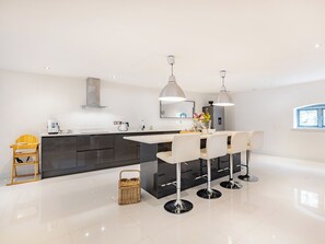 A modern kitchen with a central island, pendant lighting, and a dining area with bar stools.