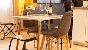 Un coin repas moderne avec une table ronde, deux chaises, une bouteille de vin et des verres.