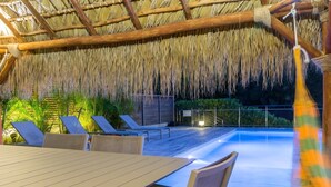 A wooden deck with a pool, lounge chairs, and a table. - Apartment-Royal-Wet room-Partial sea view-Piscine et Salle de Sport (La Trinité)