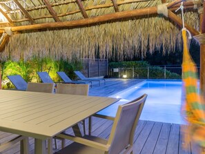 Ein Poolbereich mit Holzterrasse, Liegestühlen und einem Tisch.