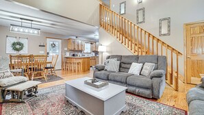A spacious living room with a grey sofa, a white coffee table, and a wooden staircase. - Spacious Home in Helen w/ Porch & Balcony! (Helen)