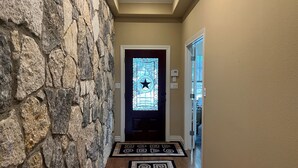 Un pasillo con pared de piedra, una puerta con un vitral en forma de estrella y una alfombra estampada.