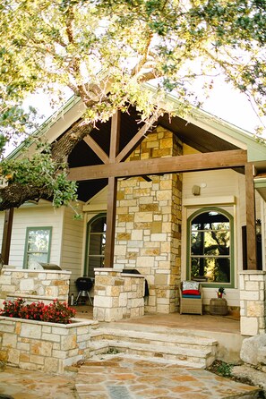 A stone house with a porch, a stone fireplace, and a covered outdoor seating area.