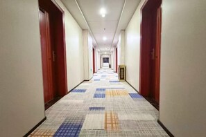 A hotel corridor with doors on both sides, a patterned carpet, and a framed picture on the wall. - Jinhe Hotel (Lanzhou)