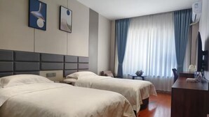 Habitación de hotel con dos camas, un escritorio, una silla, un televisor y una ventana con cortinas.