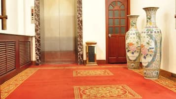 A hallway with a red carpet, a wooden door, and two large vases.