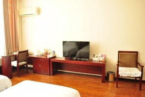 A hotel room with a wooden desk, a television, a chair, and a bed. - Jinhe Hotel (Lanzhou)