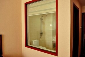 A bathroom with a glass-enclosed shower, a toilet, and a mirror framed in red. - Jinhe Hotel (Lanzhou)