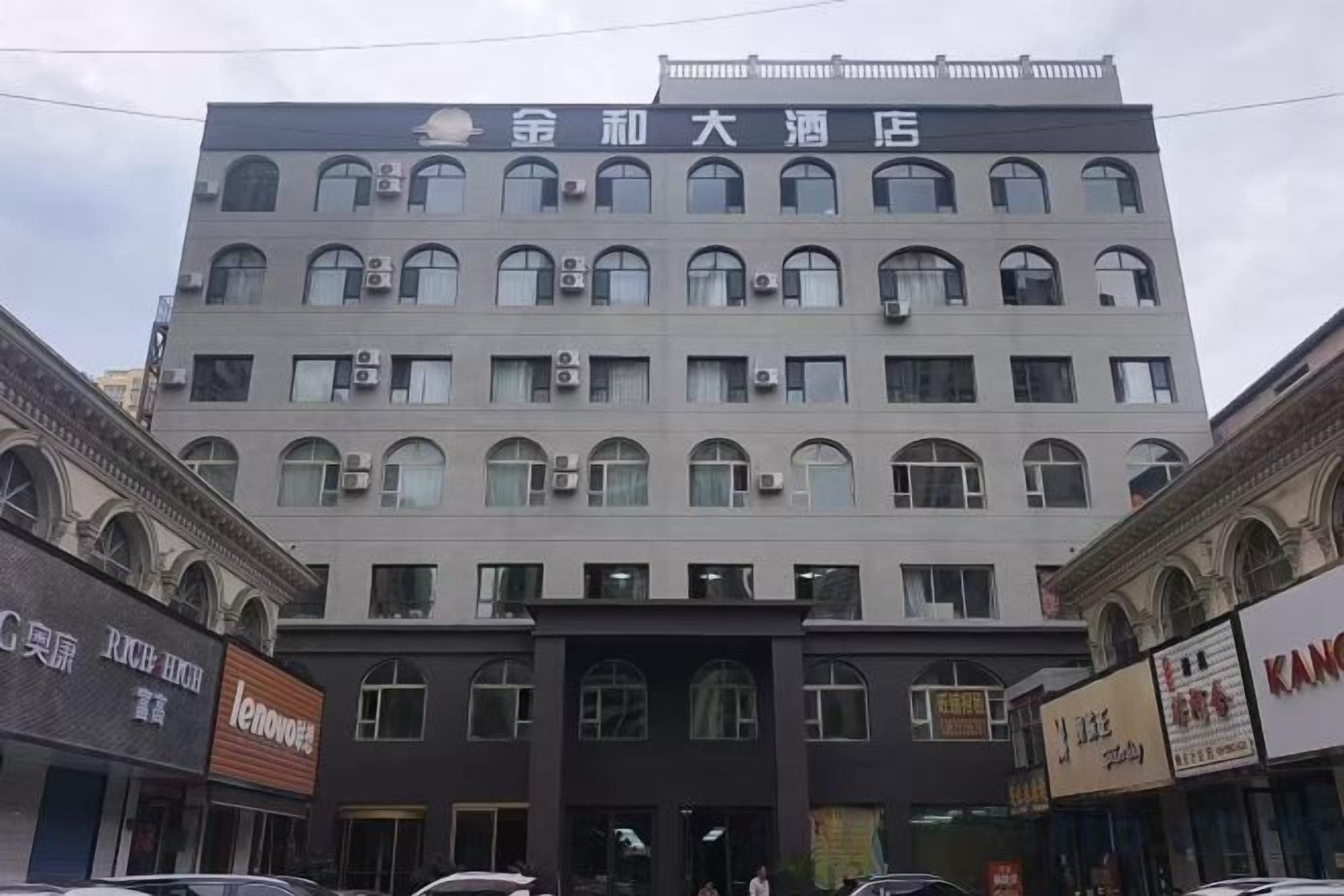 Un edificio de varios pisos con una entrada central, múltiples ventanas y letreros de negocios en la planta baja.