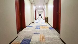 Un largo y estrecho pasillo de hotel con puertas rojas a ambos lados y una alfombra estampada.
