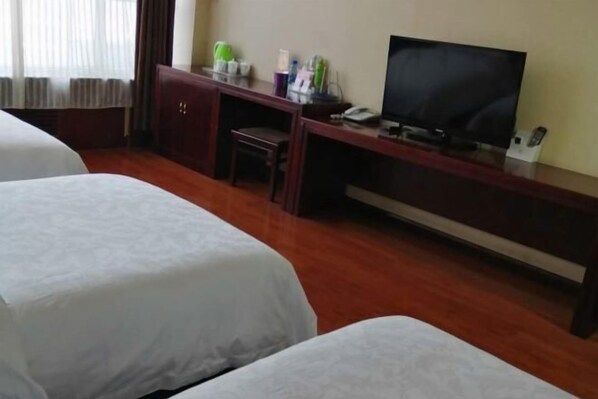 A hotel room with two beds, a desk with a TV, and a cabinet.