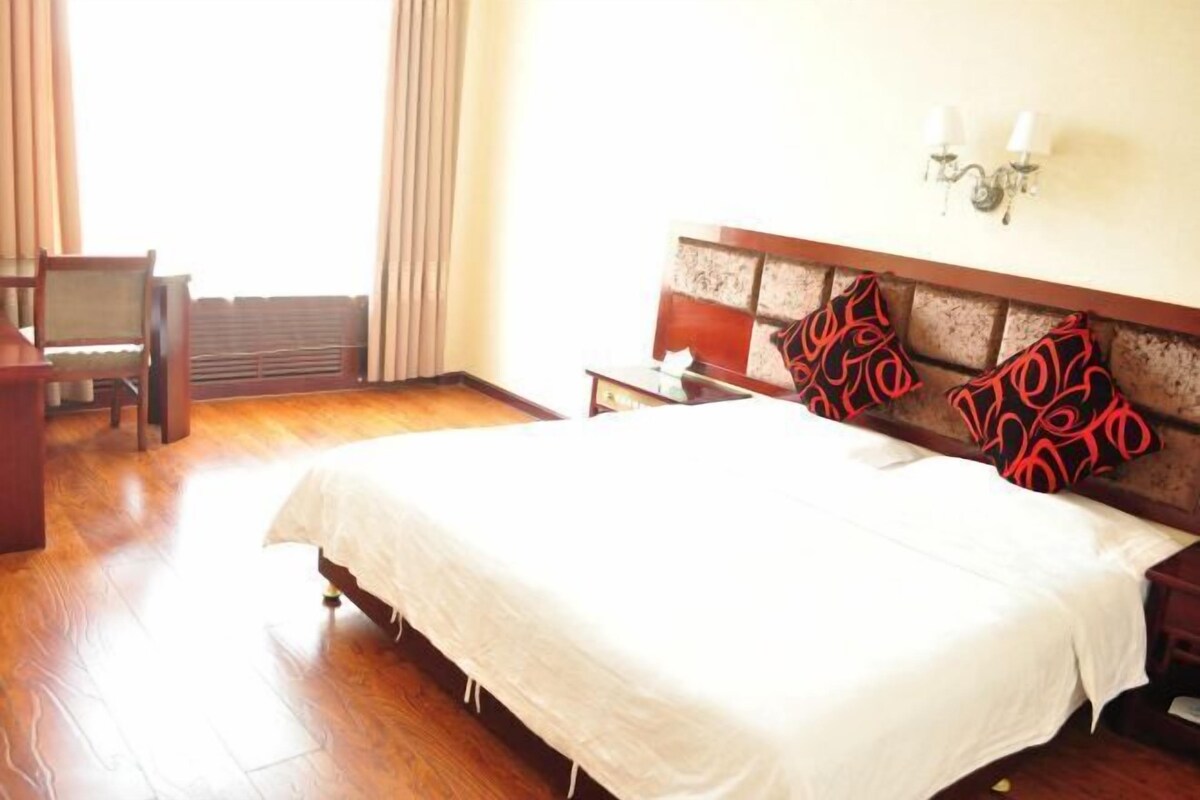 A hotel room with a large bed, a desk, and a chair.