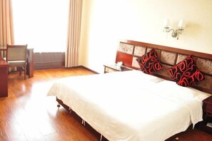 Een hotelkamer met een groot bed, een bureau en een stoel.