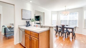 A modern kitchen with a central island, a dining area with a table and chairs, and a living space with a sofa and a coffee machine. - Fun-Filled Stay: Game Room*HOT TUB* (Spring Hill)