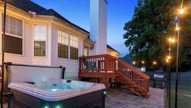A hot tub with steps, a wooden deck, and a staircase leading to a house. - Fun-Filled Stay: Game Room*HOT TUB* (Spring Hill)