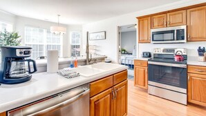 A modern kitchen with wooden cabinets, stainless steel appliances, and a large window providing natural light. - Fun-Filled Stay: Game Room*HOT TUB* (Spring Hill)