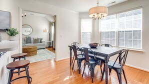 A dining area with a wooden table and chairs, a chandelier, and a view of the outside through large windows. - Fun-Filled Stay: Game Room*HOT TUB* (Spring Hill)